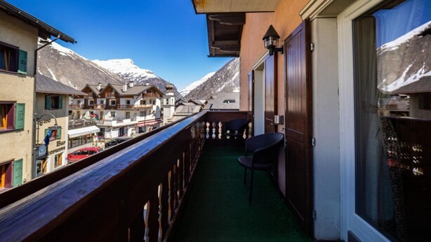 Ein Balkon mit Holzwertung, einem Stuhl und Blick auf schneebedeckte Berge.