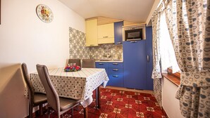 A compact kitchen with blue cabinets, a microwave, and a patterned backsplash.