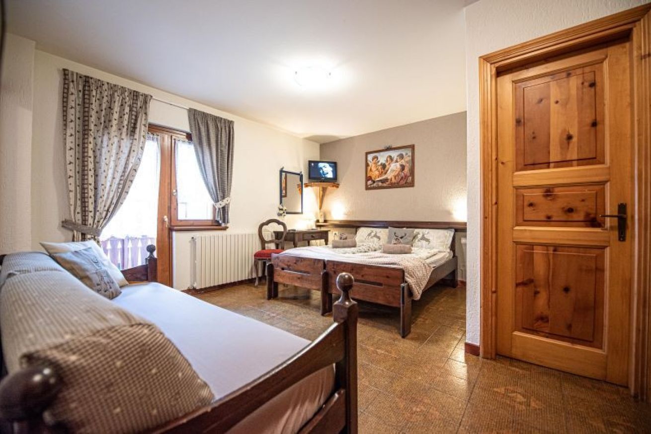 Ein Schlafzimmer mit einem Bett, einem Holzschrank, einem Fernseher und einem gerahmten Bild an der Wand.