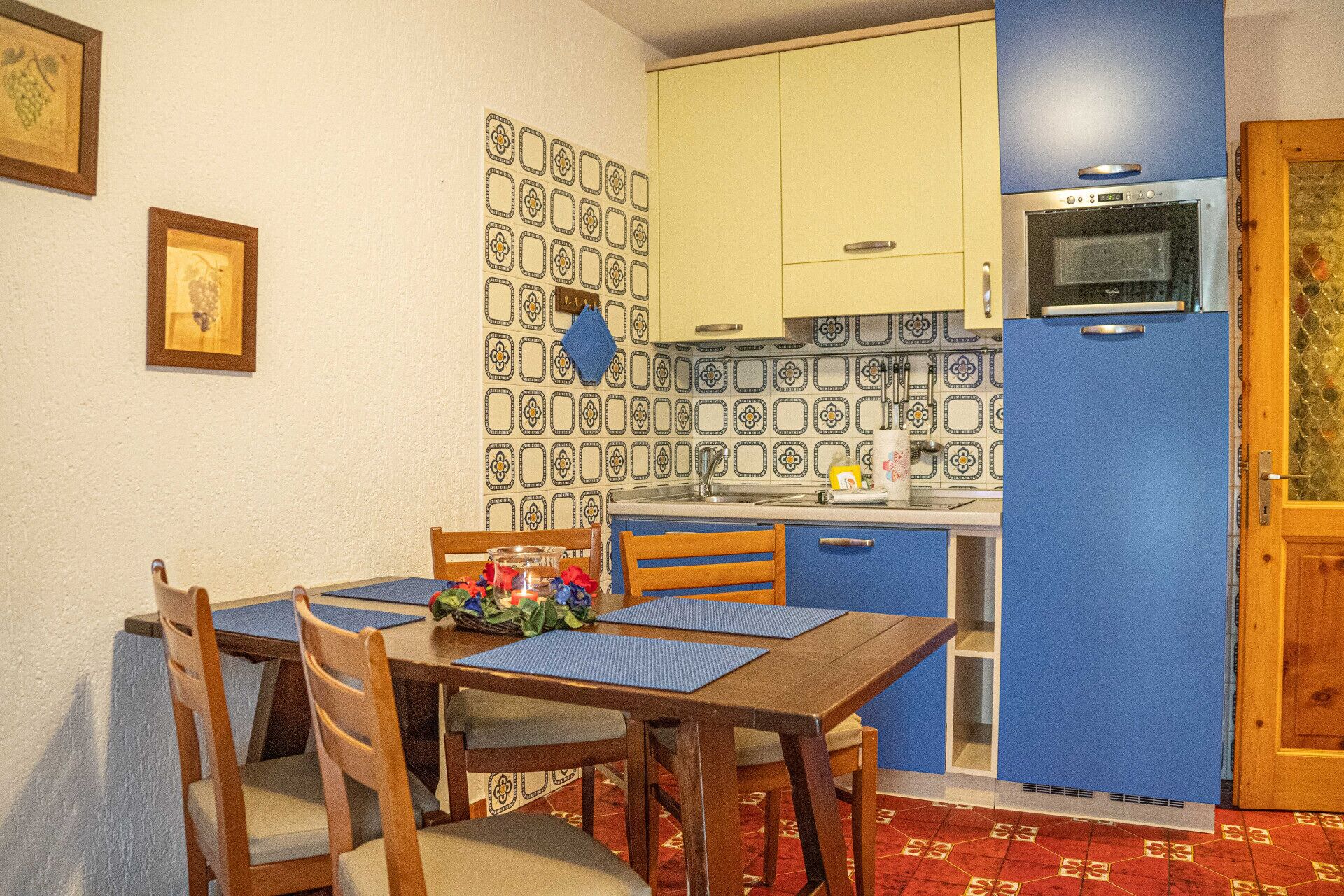 A compact kitchen with a microwave, a sink, and a patterned backsplash.