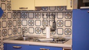 Una cocina con gabinetes azules, un lavamanos de acero inoxidable y un salpicadero con diseño.