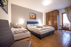 A bedroom with two beds, a wooden wardrobe, and a painting on the wall.