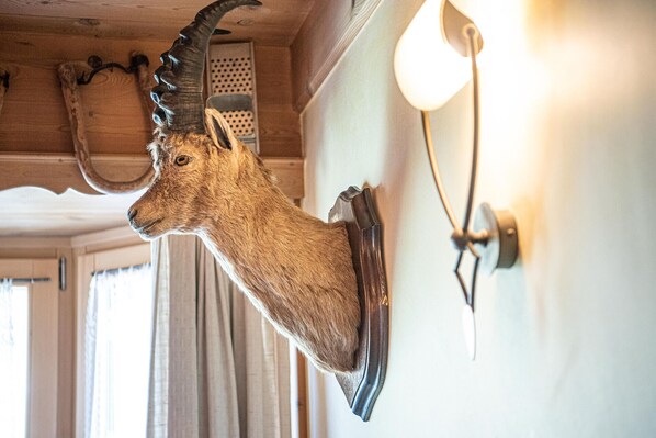 Una cabeza de venado montada en la pared, una lámpara y una ventana con cortinas.