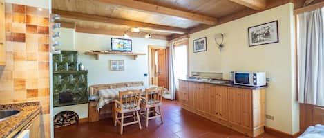 Una cocina acogedora con armarios de madera, una mesa de comedor con sillas y un televisor en un estante.