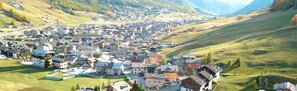 Une ville où se côtoient des bâtiments traditionnels et modernes, entourée de collines verdoyantes et dominée par un ciel dégagé.