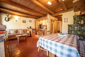 Une pièce chaleureuse avec un canapé, une table et un lit recouvert d’une couverture à carreaux. On y trouve également un coin cuisine avec des placards en bois et un réfrigérateur.