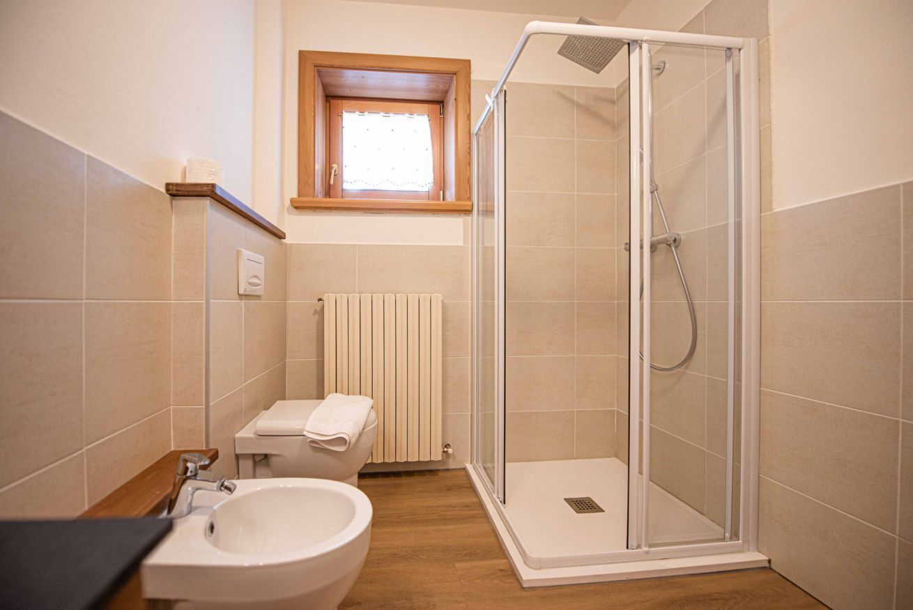 Un baño con ducha, inodoro, lavabo y una ventana sobre el inodoro.