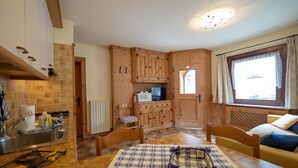 Una cocina acogedora con armarios de madera, una mesa de comedor con un mantel individual y una ventana con cortinas.