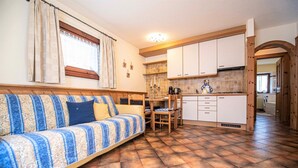 Una sala de estar acogedora con un sofá, una mesa de comedor y una zona de cocina con armarios y una estufa.