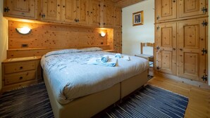 Un dormitorio estilo cabaña de madera con una cama grande, dos mesitas de noche y armarios empotrados.