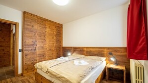 A wooden room with a bed, a nightstand, and a radiator. - The Real Wood Chalet awaits you for a vacation in comfort. (livigno)