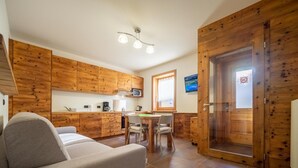 A compact living space with a kitchenette, a dining area, and a sofa. - The Real Wood Chalet awaits you for a vacation in comfort. (livigno)