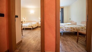 Une chambre d’hôtel avec deux lits, un plancher en bois et une poignée de porte bien visible.