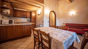 Une cuisine chaleureuse avec des meubles en bois et un four à micro-ondes, un coin repas avec une table et des chaises, et un canapé rouge en arrière-plan.