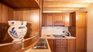 Une cuisine avec des meubles en bois, un évier en acier inoxydable et un plan de travail blanc.