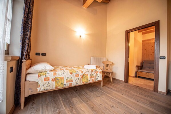 Une chambre avec un lit en bois, une table de chevet, une chaise et un plancher en bois.
