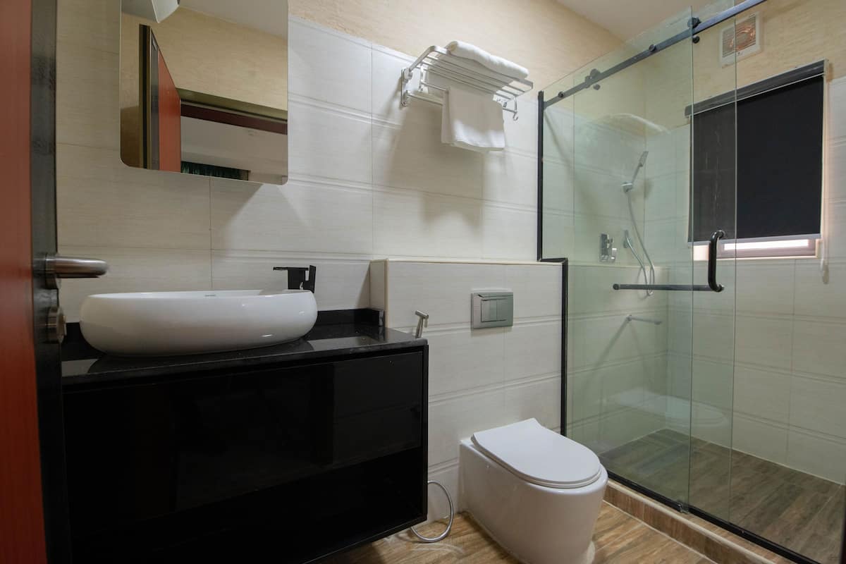 A modern bathroom with a glass-enclosed shower, a white sink, and a black vanity.