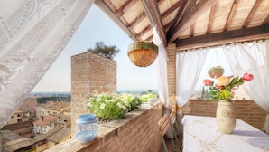 En balkon med udsigt over bybilledet, en plantekurv, en vase med blomster og en dekorativ lanterne.