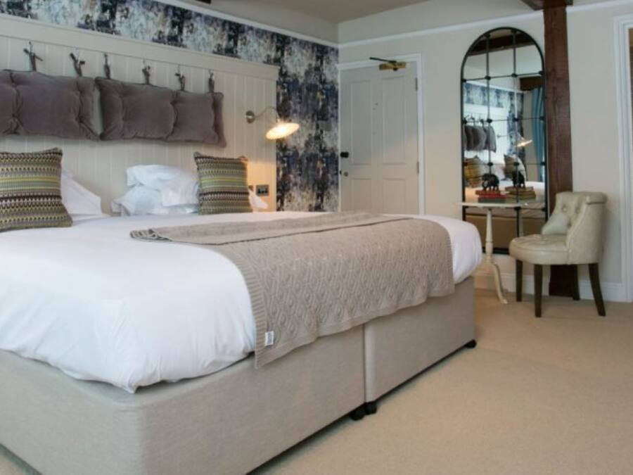 A bedroom with a large bed, a chair, a mirror, and a wardrobe.