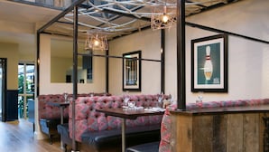 A restaurant with a wooden bar, cushioned seating, and framed artwork on the walls. - The Elephant at the Market (Newbury)