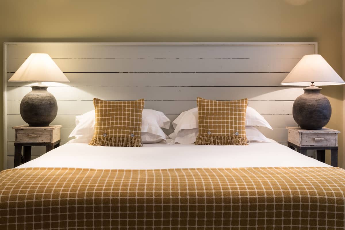 A bed with a checkered bedspread, two lamps on nightstands, and a white headboard.