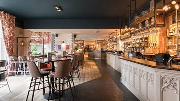 A modern bar area with a long counter, bar stools, and shelves stocked with bottles.