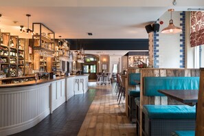 A bar area with wooden shelves, a bar counter, and seating with blue cushions. - The Florentine (Sheffield)