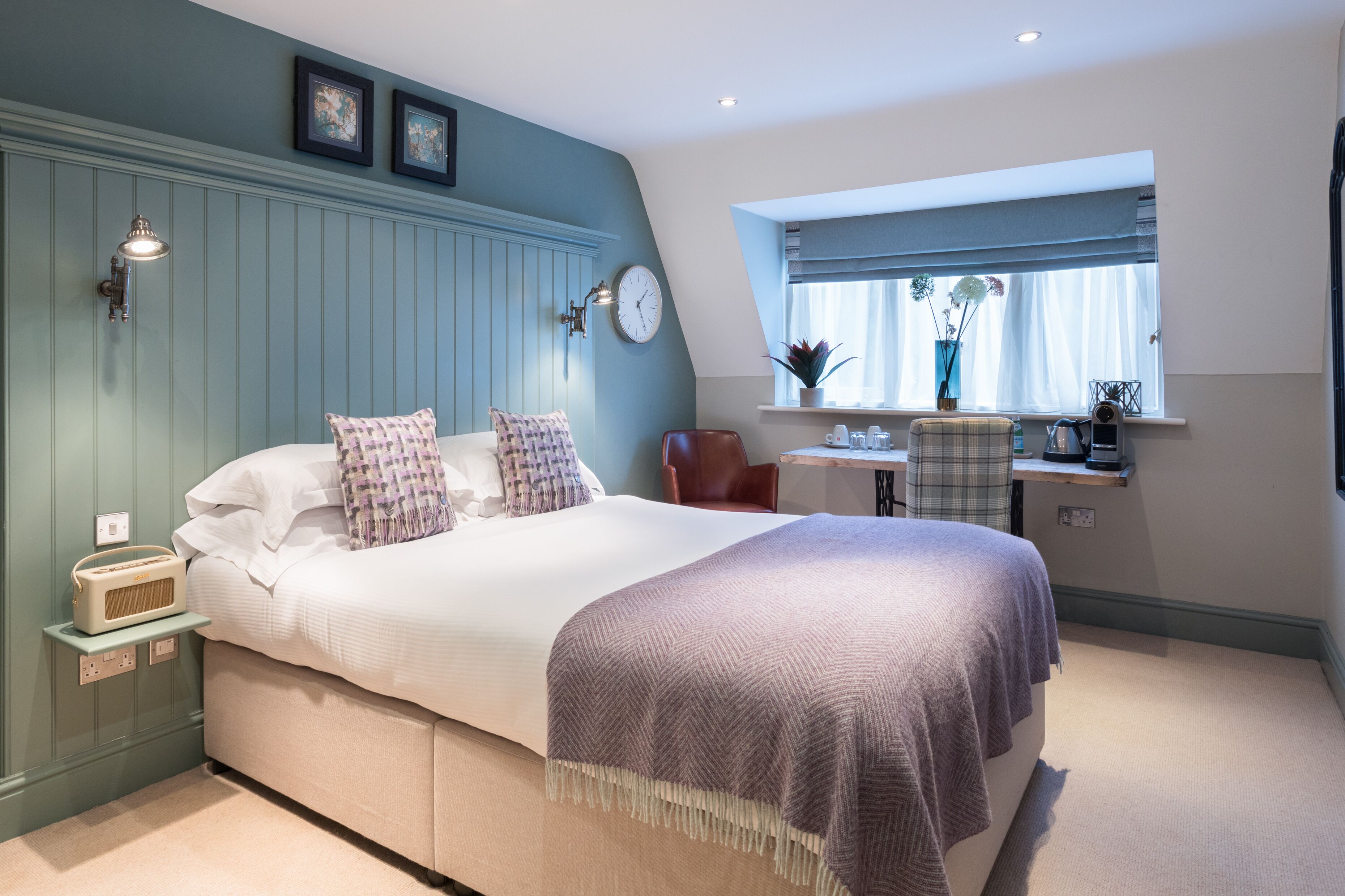 A bedroom with a bed, bedside table, lamp, and a window with curtains.