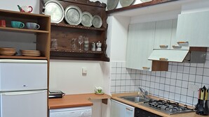 A compact kitchen with white appliances, a wooden countertop, and a tiled backsplash. - Azalea Residence (Orta San Giulio)
