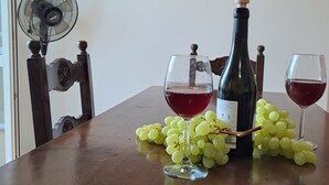 A wooden table with a wine bottle, two glasses of red wine, and a bunch of green grapes. - Azalea Residence (Orta San Giulio)