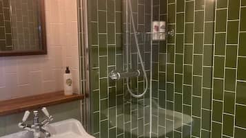 A bathroom with a glass-enclosed shower, a white sink, and a mirror above it.