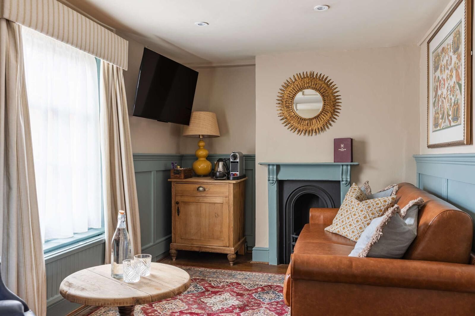 A living room with a fireplace, a sofa, a round coffee table, and a television mounted on the wall.