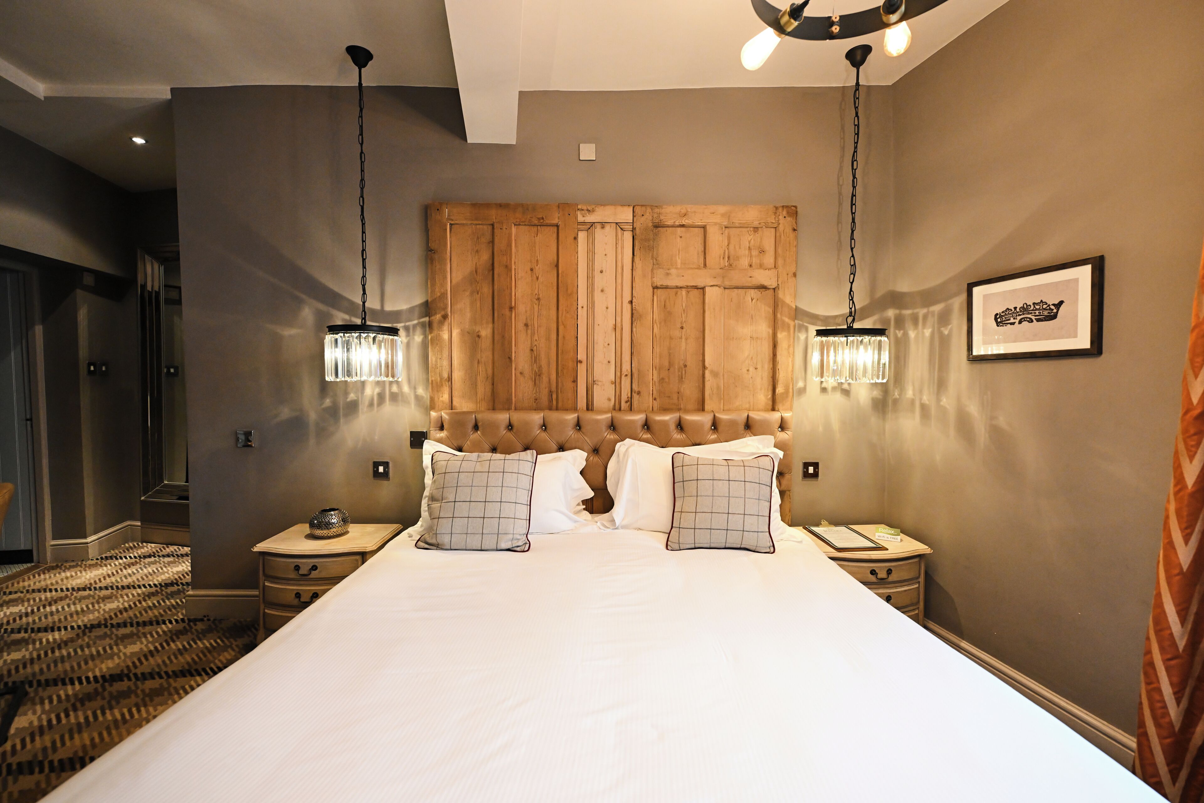 A large bed with a wooden headboard, two bedside tables with lamps, and a framed picture on the wall.