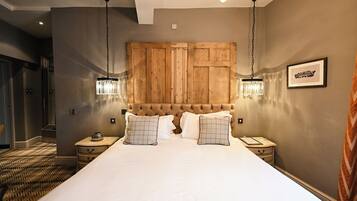 A large bed with a wooden headboard, two bedside tables with lamps, and a framed picture on the wall.