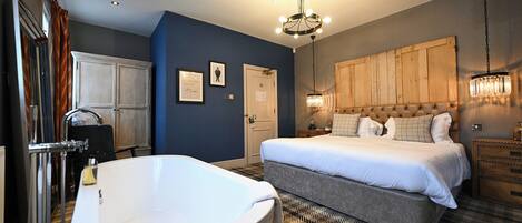 Quarto com cama grande, banheira e cabeceira de madeira.