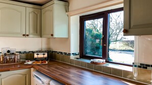 Una cocina con encimeras de madera, una ventana con vistas a árboles y un tostador sobre la encimera.
