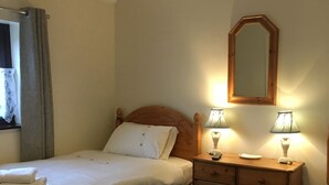 Una habitación de hotel con dos camas, un aparador de madera, un espejo y dos lámparas de noche.