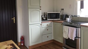 Una cocina compacta con microondas, horno y armarios de madera.