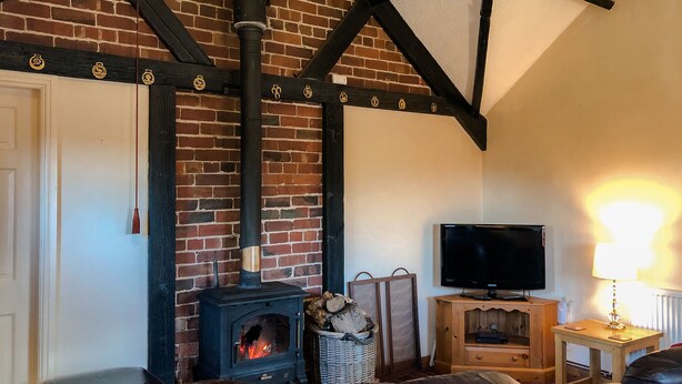 Una sala de estar acogedora con chimenea de ladrillo, asientos de cuero y televisor.