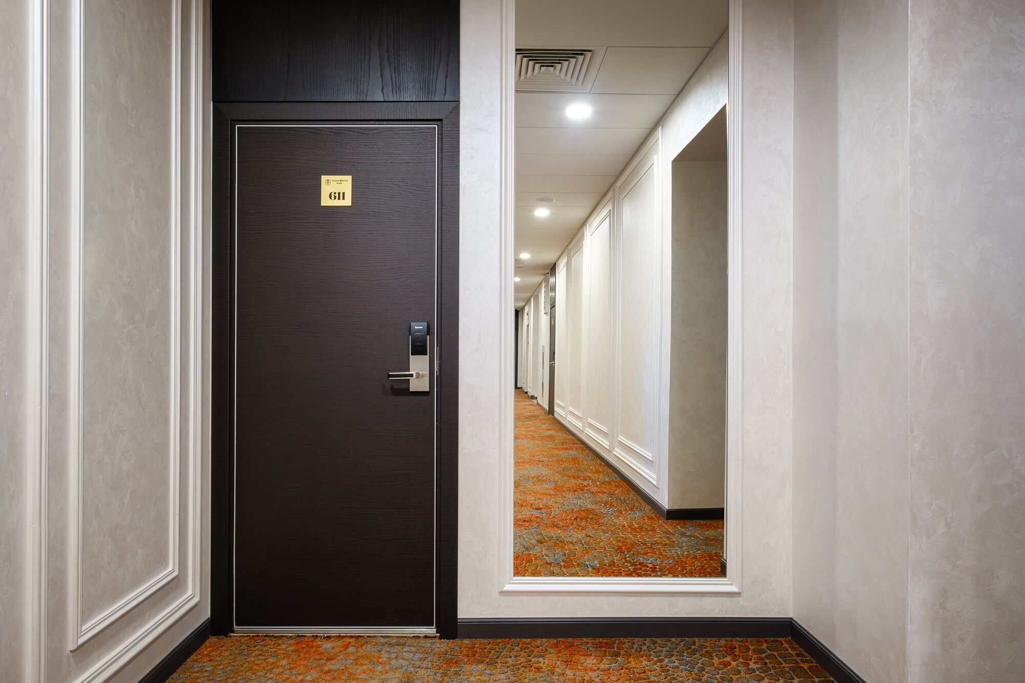 A hotel hallway with a dark wooden door labeled "G11" and a carpeted floor.