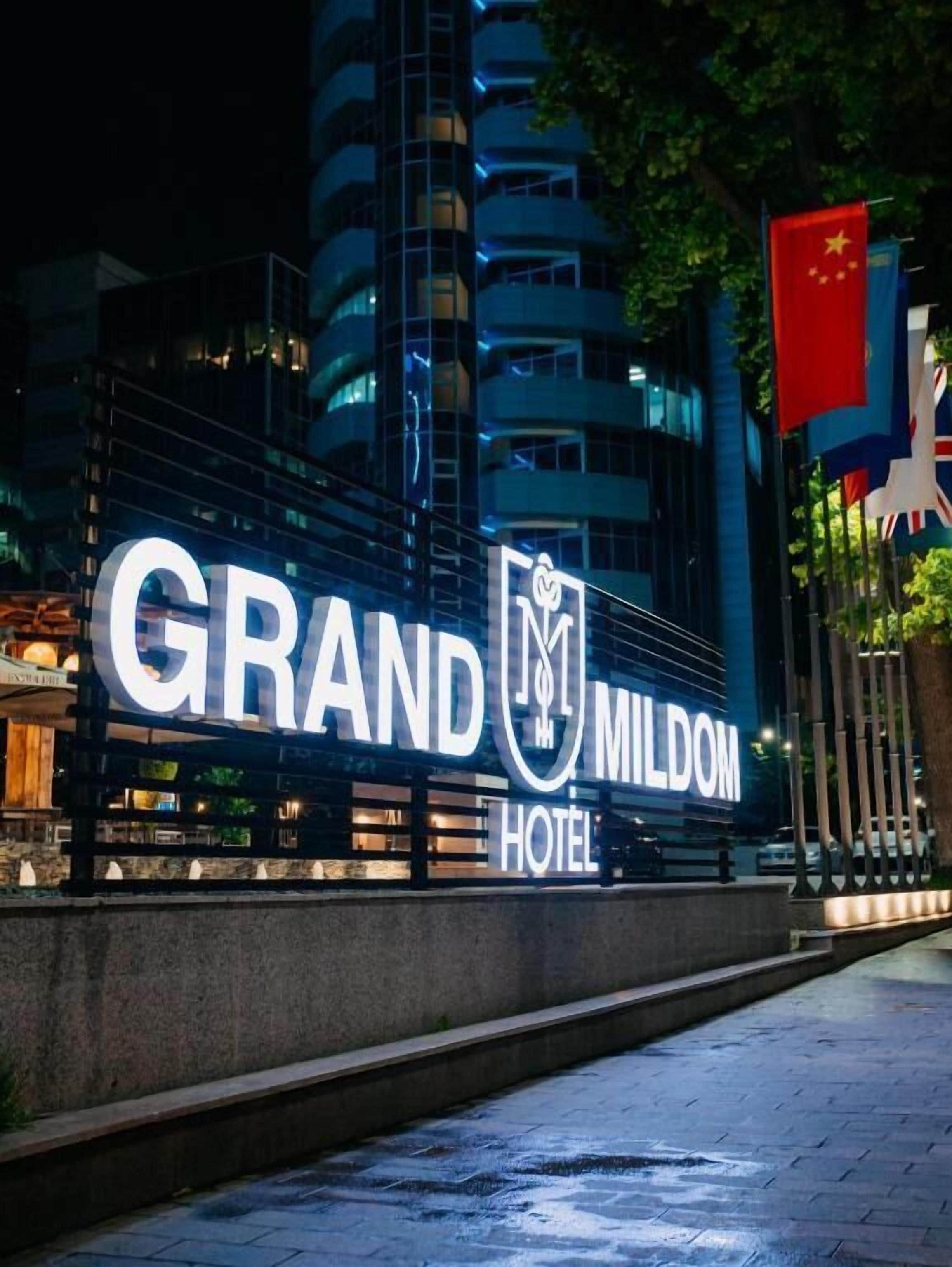The exterior of the Grand MILDOM Hotel with its illuminated signage.