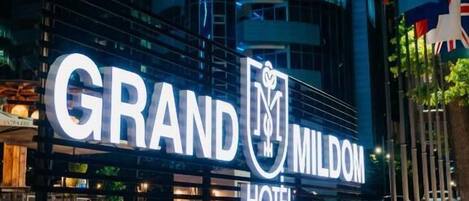 The exterior of the Grand MILDOM Hotel with its illuminated signage.