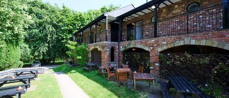 A brick building with outdoor seating and a covered patio area.