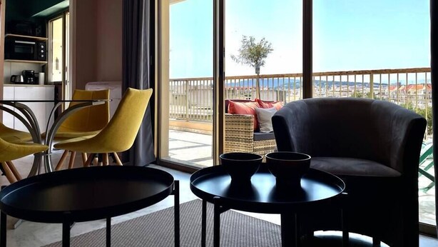 A modern hotel room with a balcony, a dining area with chairs and tables, and a kitchenette. - RoofTop Apartment - Quartier Croisette (Cannes)