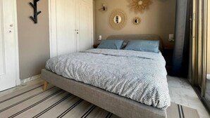 A bedroom with a bed, a wardrobe, a mirror, and a decorative wall piece. - RoofTop Apartment - Quartier Croisette (Cannes)