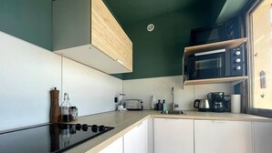 A modern kitchen with a black stove, white cabinets, a microwave, and a coffee maker. - RoofTop Apartment - Quartier Croisette (Cannes)