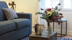 A living room with a blue sofa, a patterned pillow, a metal bucket with glasses, a vase with flowers, and a lamp. - Louvre Opera Design (Paris)