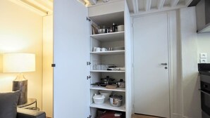 A compact kitchen with white cabinetry, a stove, and various kitchenware.