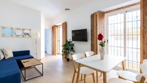 A modern living room with a blue sofa, a coffee table, and a dining area with a white table and chairs. - San Lorenzo 4 - One Bedroom Apartment, Sleeps 4 (Sevilla)