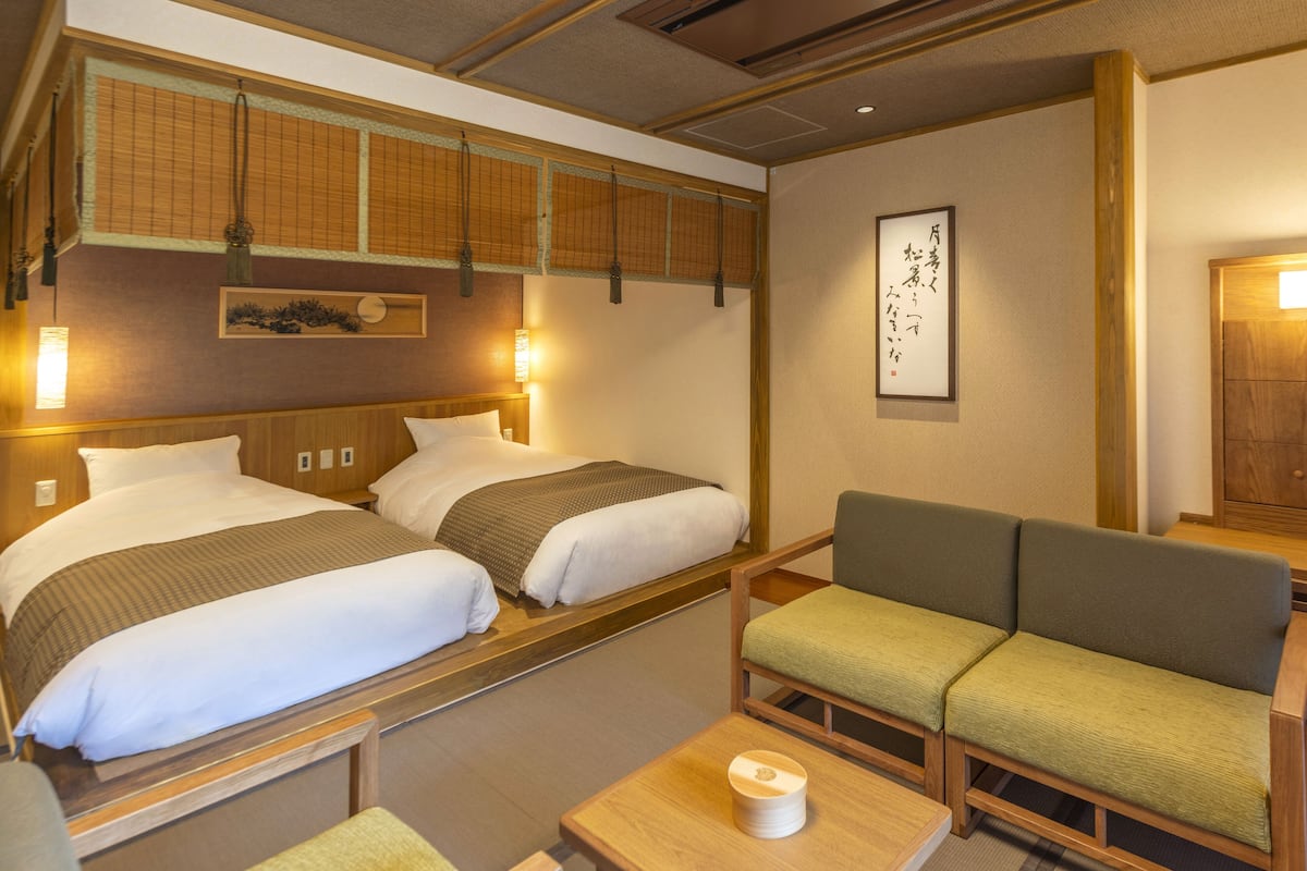 A hotel room with two beds, a sofa, and a small table.